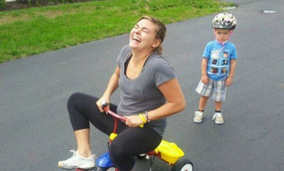 Mom on a tricycle while preschooler looks sad.