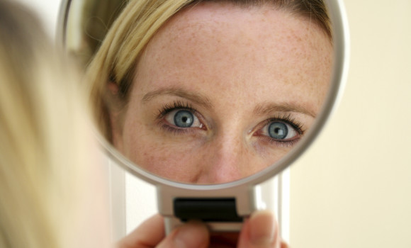 Woman looks at her reflection in a mirror